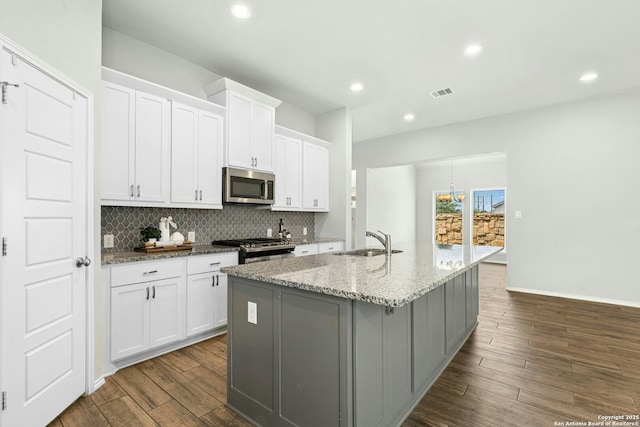 9304 Aggie Run, San Antonio, TX 78254 - kitchen with stainless steel appliances, a sink, dark wood-type flooring, an island with sink, and backsplash