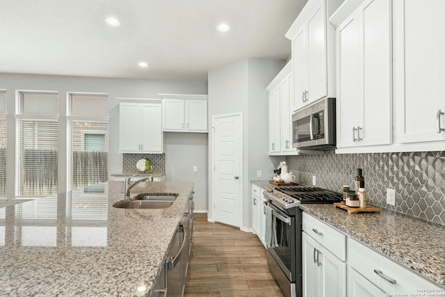9304 Aggie Run, San Antonio, TX 78254 - kitchen featuring appliances with stainless steel finishes, a sink, white cabinetry, dark wood finished floors, and baseboards