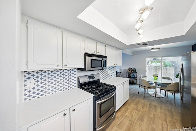 14201 Modesta Pl, San Antonio, TX 78247 - kitchen with stainless steel appliances, a raised ceiling, light countertops, and white cabinetry