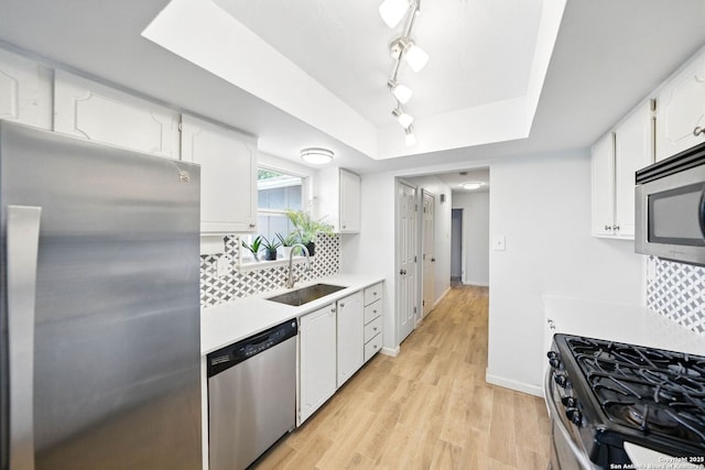 14201 Modesta Pl, San Antonio, TX 78247 - kitchen featuring appliances with stainless steel finishes, a sink, a raised ceiling, light countertops, and white cabinetry