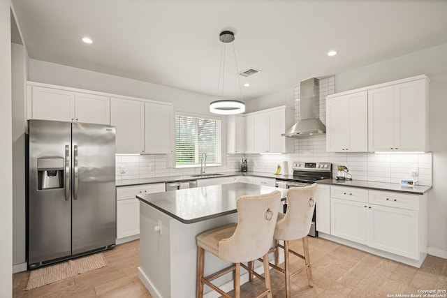 1226 Wyoming Unit 201, San Antonio, TX 78203 - kitchen featuring stainless steel appliances, wall chimney exhaust hood, a sink, white cabinets, and decorative backsplash