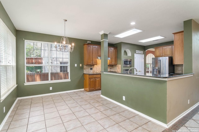 2610 Plum Holw, San Antonio, TX 78258 - kitchen with appliances with stainless steel finishes, decorative backsplash, a chandelier, dark countertops, and light tile patterned flooring