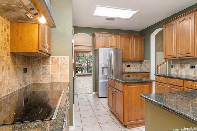 2610 Plum Holw, San Antonio, TX 78258 - kitchen featuring stainless steel fridge, arched walkways, wall chimney exhaust hood, and black electric stovetop