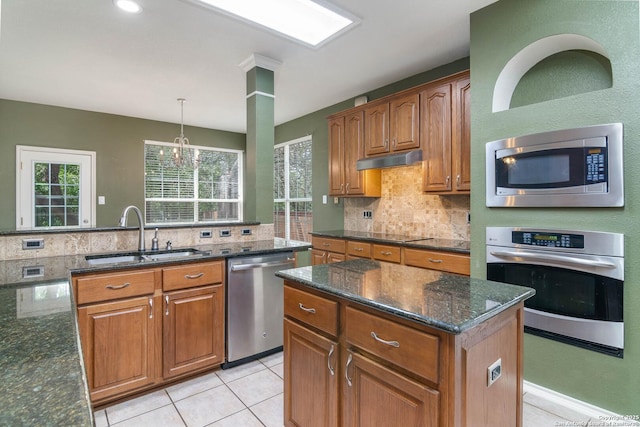2610 Plum Holw, San Antonio, TX 78258 - kitchen with appliances with stainless steel finishes, a sink, decorative backsplash, under cabinet range hood, and brown cabinets
