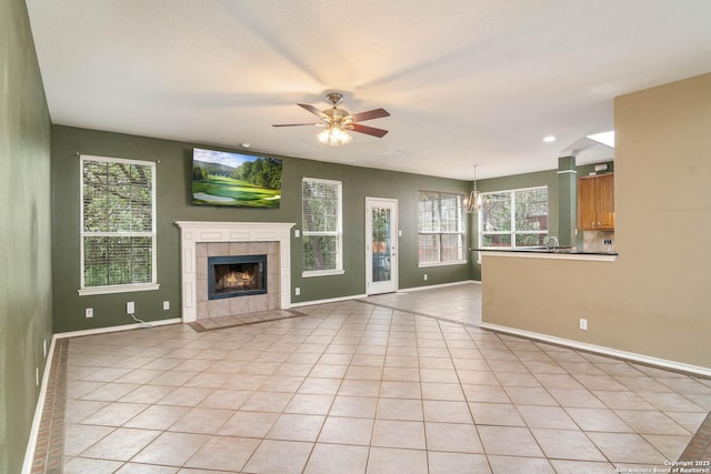 2610 Plum Holw, San Antonio, TX 78258 - unfurnished living room with healthy amount of natural light, ceiling fan, a tiled fireplace, baseboards, and recessed lighting