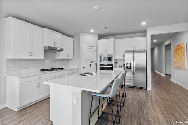 10247 Juniper Oaks, Boerne, TX 78006 - kitchen featuring stainless steel appliances, a sink, baseboards, light wood-style floors, and under cabinet range hood