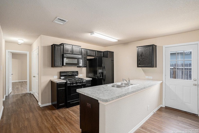7406 Snapdragon Ct, Converse, TX 78109 - kitchen featuring black appliances, a sink, dark wood-type flooring, a peninsula, and a textured ceiling