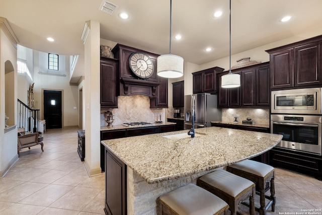 26019 Red Heron, San Antonio, TX 78261 - kitchen with appliances with stainless steel finishes, dark brown cabinetry, a kitchen bar, light stone counters, and recessed lighting