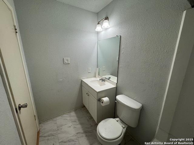2854 Cherry Fld, San Antonio, TX 78245 - bathroom with marble finish floors, vanity, toilet, and a textured wall