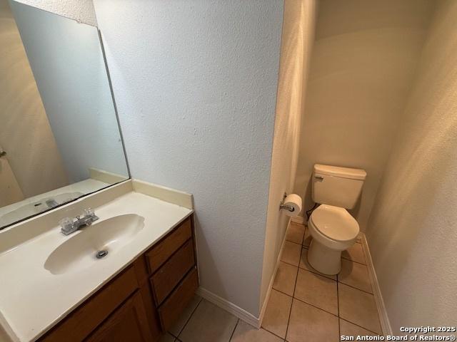 2854 Cherry Fld, San Antonio, TX 78245 - bathroom featuring toilet, vanity, tile patterned floors, a textured wall, and baseboards