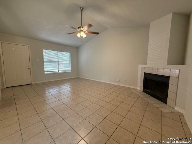 2854 Cherry Fld, San Antonio, TX 78245 - unfurnished living room featuring light tile patterned floors, vaulted ceiling, a ceiling fan, a tile fireplace, and baseboards