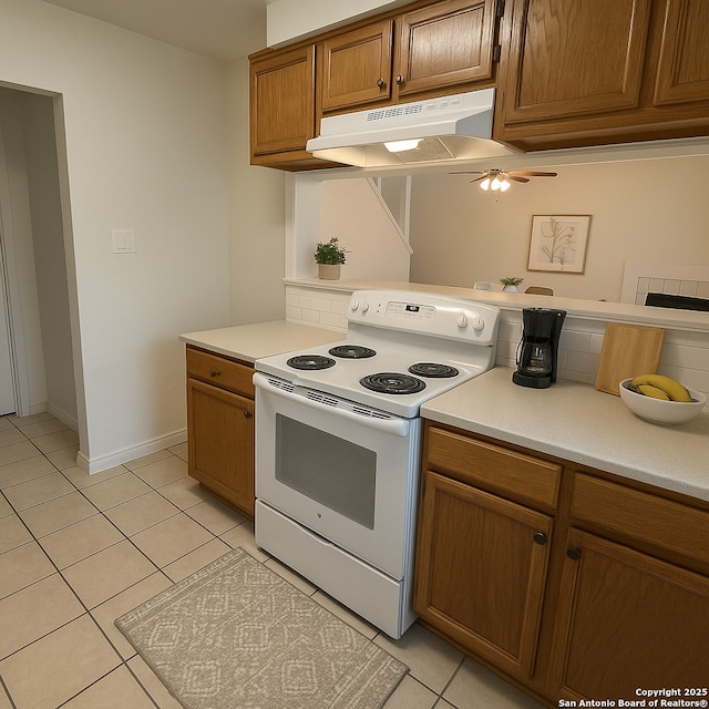 2854 Cherry Fld, San Antonio, TX 78245 - kitchen with white electric range, under cabinet range hood, light tile patterned flooring, light countertops, and brown cabinets