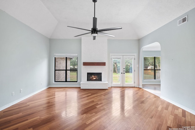 27026 Wooded Acres, San Antonio, TX 78260 - unfurnished living room featuring ceiling fan, vaulted ceiling, wood finished floors, arched walkways, and a brick fireplace