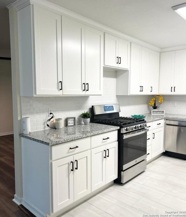 258 Galway, San Antonio, TX 78223 - kitchen with appliances with stainless steel finishes, light stone counters, decorative backsplash, and white cabinetry