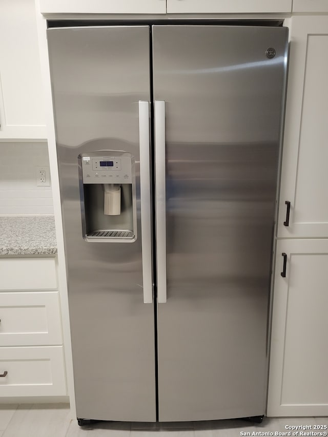 258 Galway, San Antonio, TX 78223 - detailed view of stainless steel fridge with ice dispenser, white cabinets, and light stone counters