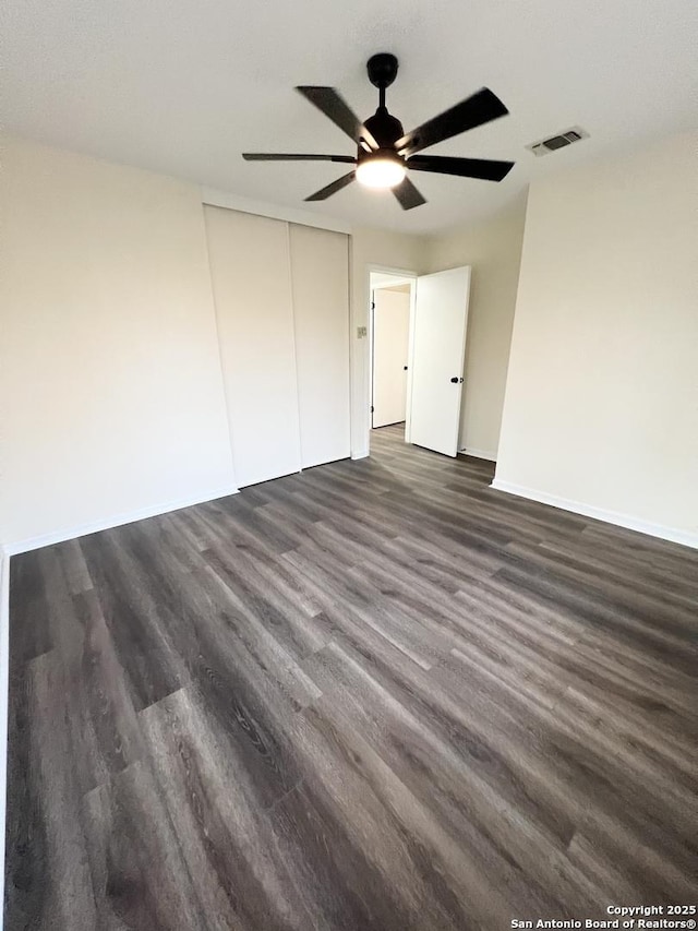 258 Galway, San Antonio, TX 78223 - unfurnished bedroom with dark wood-type flooring, baseboards, a ceiling fan, and a closet