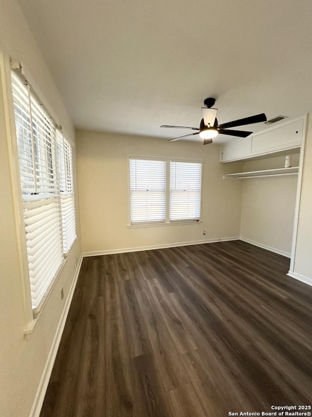258 Galway, San Antonio, TX 78223 - unfurnished bedroom with dark wood-style flooring, baseboards, multiple windows, and ceiling fan