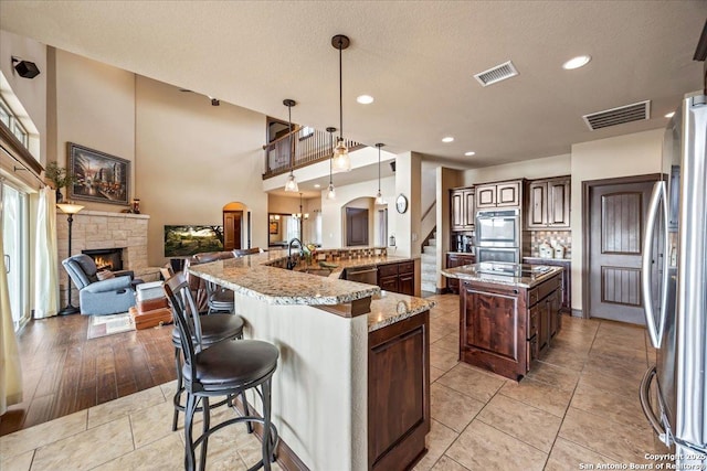 406 Breathless View St, San Antonio, TX 78260 - kitchen featuring a large island with sink, a fireplace, arched walkways, open floor plan, and a sink