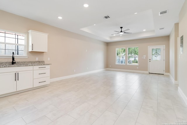 127 Hopi, San Antonio, TX 78211 - unfurnished living room featuring ceiling fan, a raised ceiling, a sink, recessed lighting, and baseboards