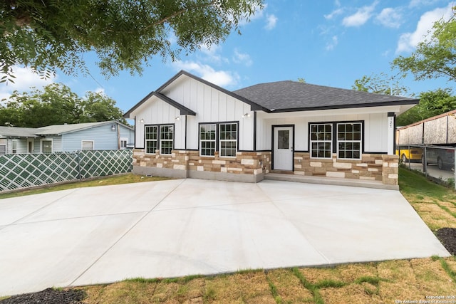 127 Hopi, San Antonio, TX 78211 - rear view of house featuring board and batten siding, a shingled roof, stone siding, and a patio