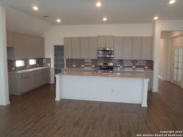 5919 Corsicana, Seguin, TX 78155 - kitchen featuring stainless steel appliances, tasteful backsplash, a kitchen island with sink, light countertops, and vaulted ceiling