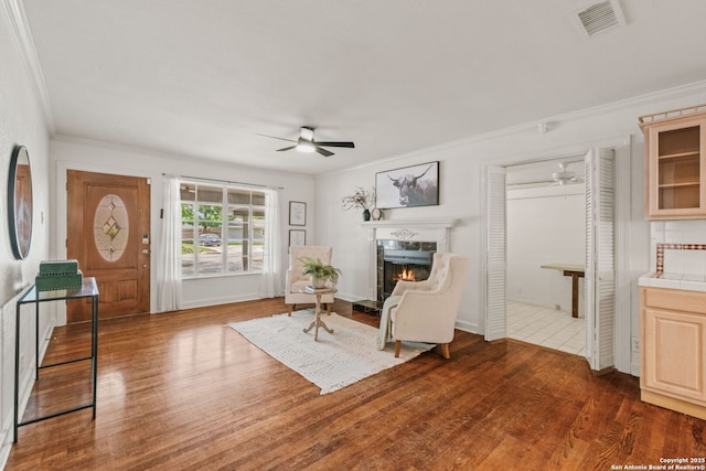 219 Ridgehaven, San Antonio, TX 78209 - sitting room with a ceiling fan, crown molding, a lit fireplace, and dark wood-style flooring