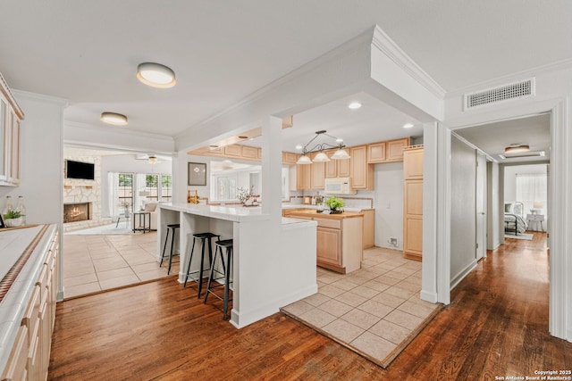 219 Ridgehaven, San Antonio, TX 78209 - kitchen featuring white microwave, light brown cabinets, ornamental molding, open floor plan, and light countertops