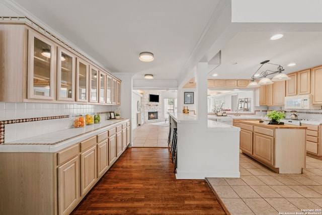 219 Ridgehaven, San Antonio, TX 78209 - kitchen with white microwave, light brown cabinetry, glass insert cabinets, tasteful backsplash, and a fireplace