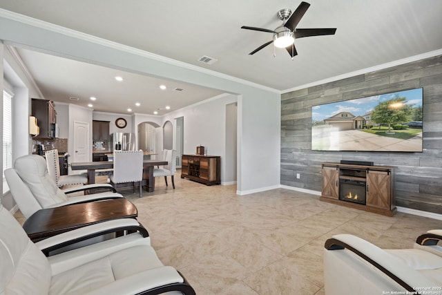 13818 Cohan Way, San Antonio, TX 78253 - living room featuring an accent wall, wood walls, arched walkways, ceiling fan, and crown molding