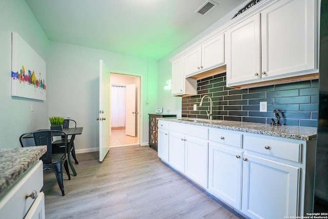 555 Hansford, San Antonio, TX 78210 - kitchen featuring a sink, white cabinetry, tasteful backsplash, light wood-style flooring, and baseboards