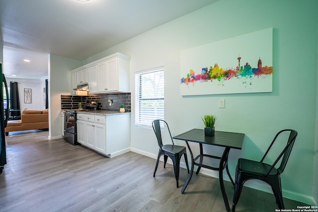 555 Hansford, San Antonio, TX 78210 - kitchen with black electric range oven, light wood-style floors, decorative backsplash, and white cabinetry