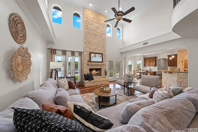 154 Lake View Dr, Boerne, TX 78006 - living room featuring a stone fireplace, a ceiling fan, wood finished floors, a towering ceiling, and arched walkways