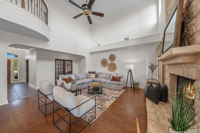 154 Lake View Dr, Boerne, TX 78006 - living area featuring arched walkways, ceiling fan, wood finished floors, a towering ceiling, and a lit fireplace