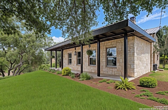 177 Ten W Dr, Comfort, TX 78013 - view of front facade with stone siding, a standing seam roof, a front lawn, a chimney, and metal roof