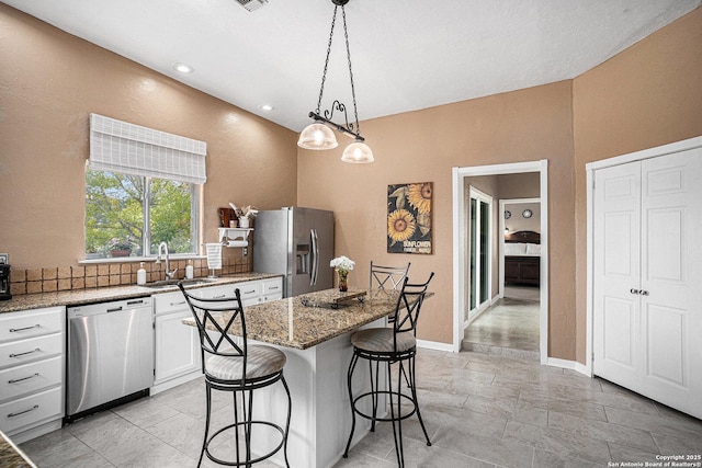 177 Ten W Dr, Comfort, TX 78013 - kitchen featuring appliances with stainless steel finishes, a sink, a breakfast bar area, light stone countertops, and white cabinets