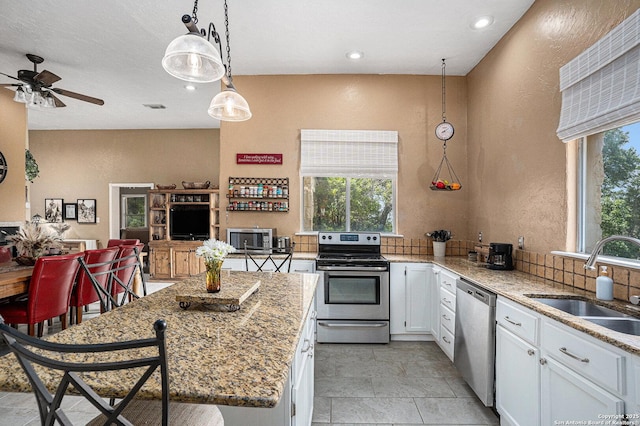 177 Ten W Dr, Comfort, TX 78013 - kitchen with stainless steel appliances, a sink, a ceiling fan, white cabinetry, and a textured wall
