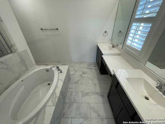 12023 Horseshoe, San Antonio, TX 78254 - bathroom featuring marble look tile flooring, vanity, and a bath