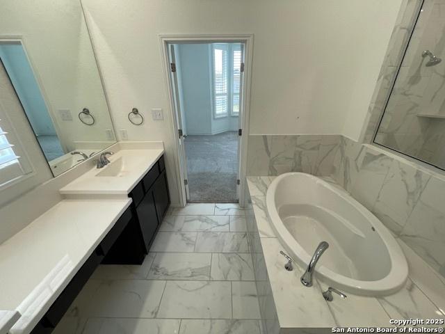 12023 Horseshoe, San Antonio, TX 78254 - full bathroom featuring marble look tiles, vanity, a bath, wainscoting, and a marble finish shower
