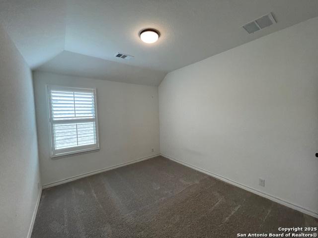 12023 Horseshoe, San Antonio, TX 78254 - spare room with dark colored carpet, vaulted ceiling, and baseboards