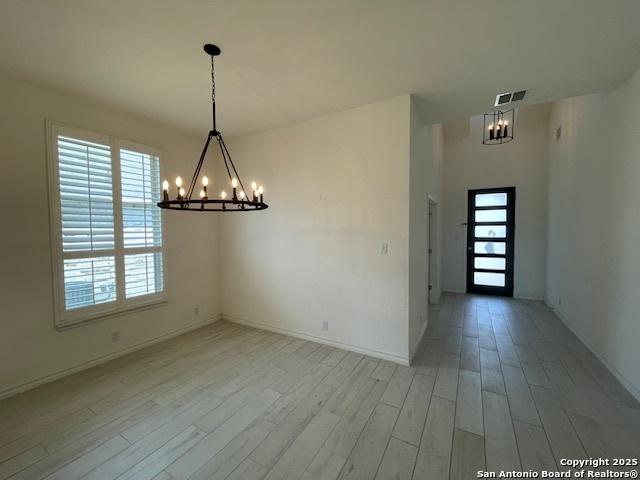 12023 Horseshoe, San Antonio, TX 78254 - unfurnished dining area with a chandelier, light wood-style floors, healthy amount of natural light, and baseboards