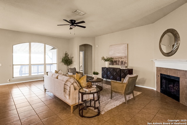 21931 Ruby Run, San Antonio, TX 78259 - tiled living area featuring arched walkways, a ceiling fan, a tiled fireplace, and baseboards