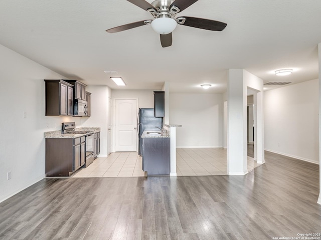7071 Capeshaw, San Antonio, TX 78252 - kitchen with stainless steel electric range, light wood-style flooring, dark brown cabinets, and baseboards