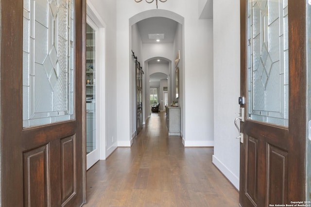 17918 Cantera Ct, San Antonio, TX 78255 - foyer featuring arched walkways, baseboards, wood finished floors, and a barn door