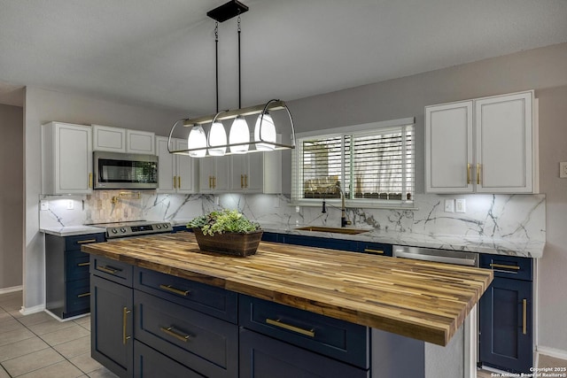 1632 Dogwood Ln, Schertz, TX 78154 - kitchen with appliances with stainless steel finishes, butcher block counters, a sink, blue cabinetry, and backsplash