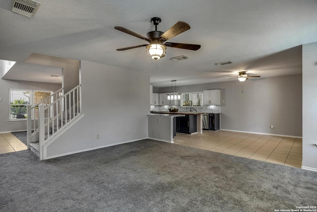 1632 Dogwood Ln, Schertz, TX 78154 - unfurnished living room featuring a ceiling fan, light tile patterned floors, light colored carpet, and healthy amount of natural light