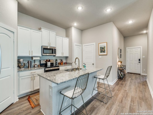 1136 Amber Lk, Seguin, TX 78155 - kitchen featuring appliances with stainless steel finishes, a sink, light wood finished floors, white cabinets, and recessed lighting