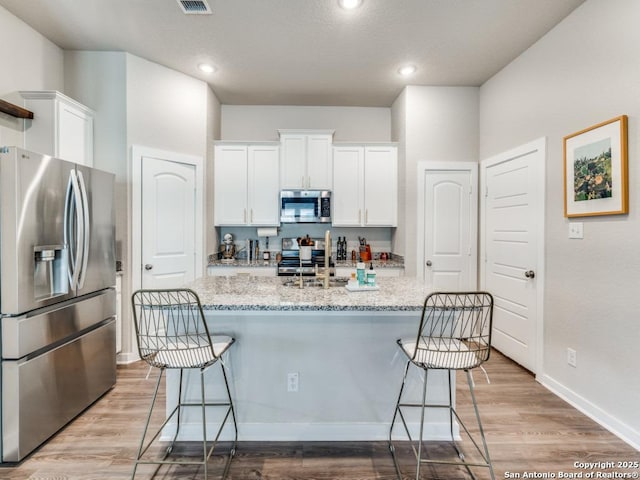 1136 Amber Lk, Seguin, TX 78155 - kitchen featuring appliances with stainless steel finishes, a sink, white cabinetry, a breakfast bar, and recessed lighting