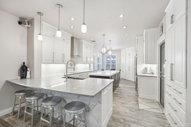 2834 Olive Ave, Schertz, TX 78154 - kitchen featuring wall chimney range hood, a peninsula, recessed lighting, light wood-style floors, and a center island