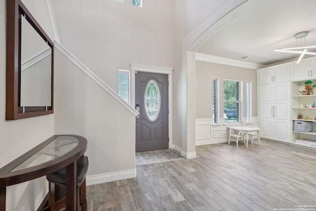 2834 Olive Ave, Schertz, TX 78154 - entryway featuring wood finished floors, ornamental molding, arched walkways, wainscoting, and a decorative wall