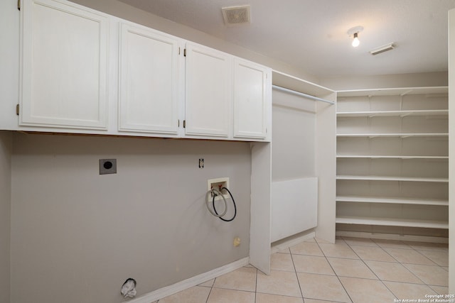 14211 Edge Pt, San Antonio, TX 78230 - laundry area featuring hookup for a washing machine, hookup for an electric dryer, cabinet space, light tile patterned floors, and baseboards